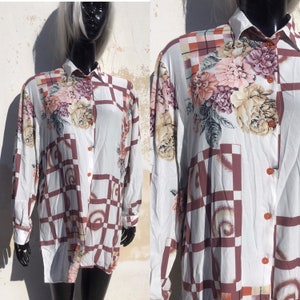 May include: A white long-sleeved button-down shirt with a geometric pattern in shades of brown and pink. The shirt features a floral print with large pink, white, and yellow flowers.