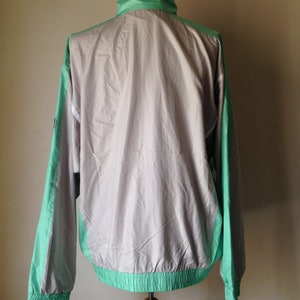 Puede incluir: Chaqueta cortavientos vintage en color gris claro con detalles en verde menta y blanco. La chaqueta tiene cuello alto, pu&ntilde;os el&aacute;sticos y dobladillo con cord&oacute;n. Las mangas y los laterales son verde menta.