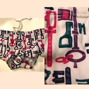 May include: White swimming trunks with a colourful key pattern. The keys are in shades of red, green, purple, and blue.