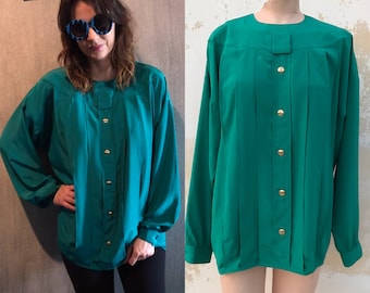 May include: A teal blue, long-sleeved blouse with a button-up front and a pleated design. The blouse has a round neckline and gold buttons.