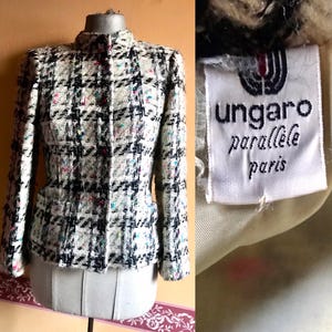 Könnte beinhalten: Eine weiße und schwarze Tweedjacke mit einem bunten Muster. Die Jacke hat einen Stehkragen und einen einzigen Knopfverschluss. Das Etikett lautet "ungaro parallele paris".