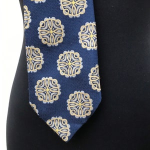 70's textured, groovy, trevira blue necktie features baroque golden/yellow round designs in dark blue background