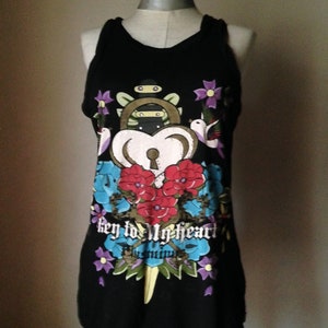 Op de afbeelding: Zwart tanktop met een kleurrijke grafische print van een sleutel, hart en bloemen. De tekst "key to my heart" is op de voorkant van het shirt gedrukt.