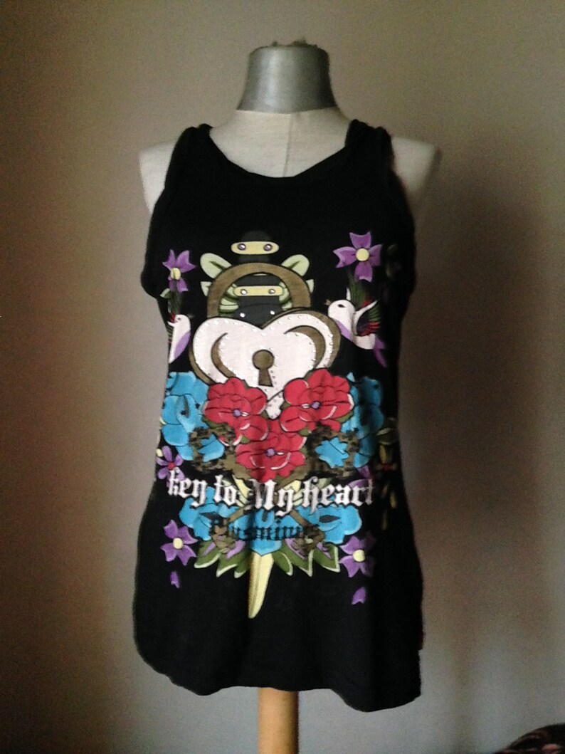 Op de afbeelding: Zwart tanktop met een kleurrijke grafische print van een sleutel, hart en bloemen. De tekst "key to my heart" is op de voorkant van het shirt gedrukt.