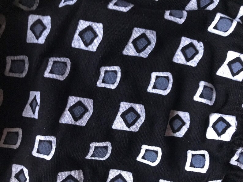 May include: Black fabric with a repeating pattern of white squares containing grey diamonds.