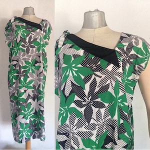 May include: A green, black, and white floral print dress with a black collar and short sleeves.