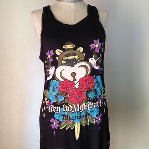 Op de afbeelding: Zwart tanktop met een kleurrijke grafische print van een sleutelgat, bloemen en vogels. De tekst "key to my heart" is onder de print gedrukt.