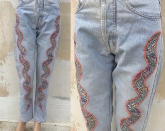 Light blue stonewashed, high waisted, pair of 90s denim features embroidered/appliqué colorful fabric in the shape of a snake at each side