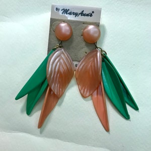 May include: A pair of dangle earrings with peach-colored flower-shaped charms and green leaf-shaped charms. The earrings are on a card that says "by Mary Ann's".
