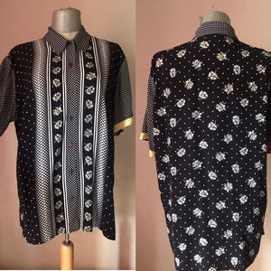 Op de afbeelding: Een zwart-wit kort mouw overhemd met knopen en een print van madeliefjes. Het overhemd heeft een witte kraag en een witte knoopsluiting. Het overhemd is gemaakt van een lichtgewicht stof en heeft een ontspannen pasvorm.