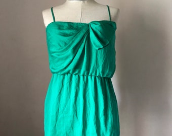 May include: A green sleeveless dress with a bow at the neckline. The dress is made of a silky material and has a fitted bodice and a flowing skirt.
