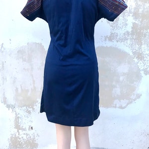 May include: A navy blue short-sleeved dress with a white, red and blue patterned band across the back.