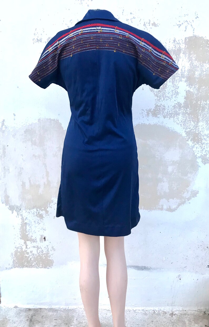 May include: A navy blue short-sleeved dress with a white, red and blue patterned band across the back.