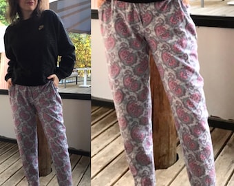 Könnte beinhalten: Eine graue Hose mit einem rosafarbenen Paisley-Muster. Die Hose hat einen breiten Bund und eine lockere Passform.