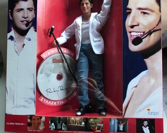 Bambola di Sakis Rouvas, cantante pop greca dell'Eurovision, alta 31 cm, rara edizione da collezione del 2005 con cofanetto contenente un DVD extra, nuova e sigillata nella sua confezione originale.