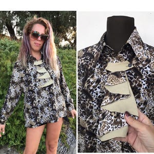 May include: A brown and white leopard print blouse with a beige ruffled collar. The blouse has long sleeves and a button-up front.