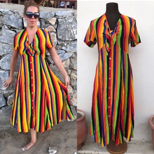 以下が含まれることがあります： Vネックとネックラインにリボンが付いたカラフルなストライプのミディ丈ドレス。ドレスはフロントにボタンが付いており、軽量な生地で作られています。