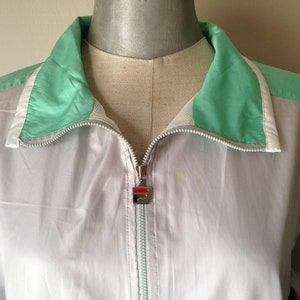 Puede incluir: Chaqueta deportiva Fila vintage en gris claro con detalles en verde menta y blanco. La chaqueta tiene una cremallera completa y un peque&ntilde;o logotipo de Fila en el tirador. El cuello y los hombros son de color verde menta.