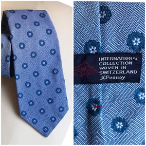 Light blue 70s bell wide necktie with thick textured fabric features geometric designs and blue daisies