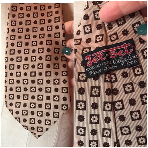 May include: A brown and white patterned tie with a black label that reads "Jet-Set 100% Polyester Collection Paris-London-N. York".