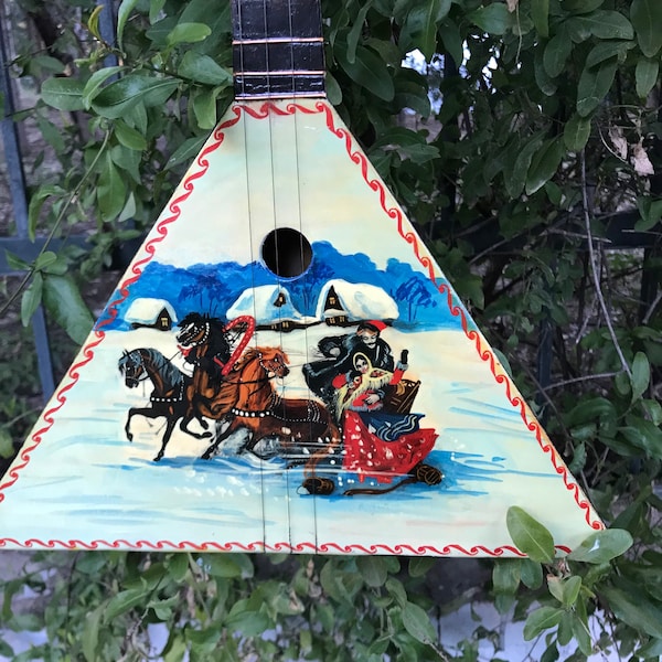 Decorative vintage musical instrument, a Russian balalaika that features hand painted front, a family in a winter landscape