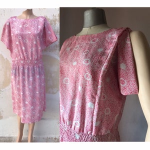 May include: A pink and white polka dot dress with a gathered waist and short sleeves. The dress has a retro style and is made of a lightweight fabric.
