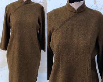 May include: A brown, long-sleeved, collared tunic dress with a mandarin collar. The dress is made of a textured fabric and has a slightly loose fit.