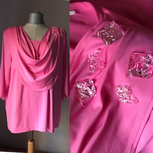 May include: A pink, long-sleeved top with a cowl neck and clear plastic embellishments.