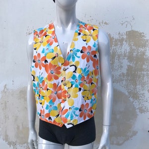80's vintage crazy kitschy vest featuring multi colored daisy pattern in orange, yellow n light blue on white background. Two front pockets