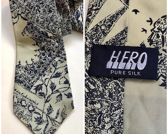 Può includere: Una cravatta di seta verde con un motivo a stampa bianco e nero. La cravatta ha un'etichetta che recita "HERO PURE SILK".