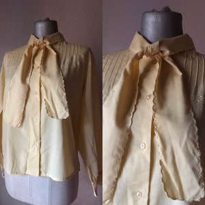 Blusa de color amarillo ocre con pajarita festoneada vintage de los años 70 con busto bordado y plisado