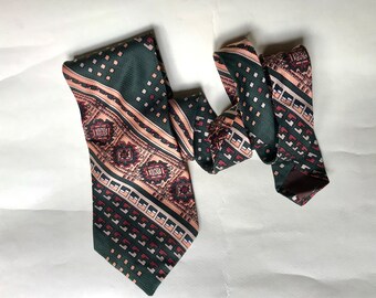 Wide bell 70s vntg necktie features various geometric designs in pine green, salmon pink and some brick red. Unique