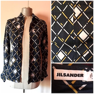 May include: A black long-sleeved shirt with a geometric pattern in white and yellow. The shirt has a button-down collar and a Jil Sander label.