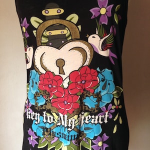 Op de afbeelding: Zwart tanktop met een kleurrijke grafische print van een hart met een sleutelgat, een hangslot, een dolk en bloemen. De tekst "key to my heart" is gedrukt op de voorkant van het tanktop.