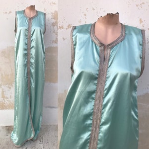 May include: A long, sleeveless, mint green satin robe with gold trim. The robe has a V-neck and a front closure.