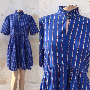 Flouncy 80s mini dress feat ruffled band collars, split neckline, interrupted vertical colorful stripes on the blue background. Girly & cool