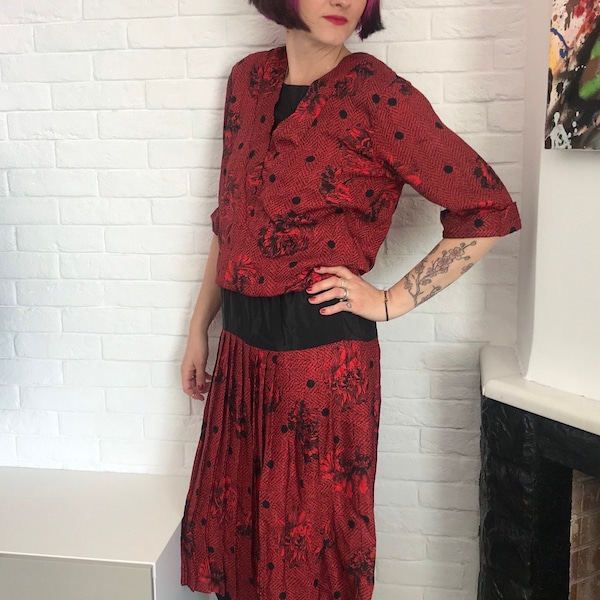 Robe gorge rouge/noire des années 80 et 40 dans le style Charleston, avec encolure en V, taille basse et jupe plissée. Par le label "Perceptions"