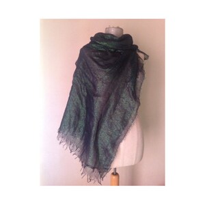 May include: A black and green sparkly scarf with a fringed edge. The scarf is draped over a mannequin.