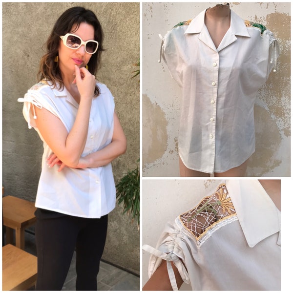 Blusa semitransparente blanca vintage de los años 80 con botones que presenta hombros recortados con intrincados bordados florales y mangas dolman fruncidas.