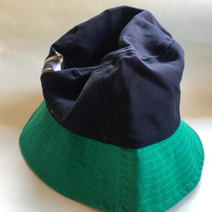Op de afbeelding: Een blauwe en groene bucket hat. De bovenkant van de hoed is blauw en de rand is groen.
