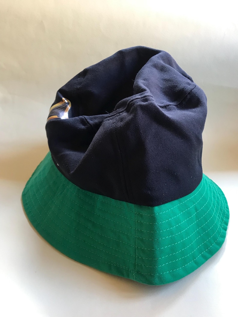 Op de afbeelding: Een blauwe en groene bucket hat. De bovenkant van de hoed is blauw en de rand is groen.