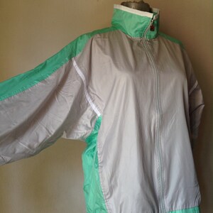 Puede incluir: Chaqueta deportiva vintage en gris, verde menta y blanco. La chaqueta tiene un cuello alto, una cremallera completa y pu&ntilde;os y dobladillo el&aacute;sticos. Las mangas y los laterales est&aacute;n acentuados con paneles verde menta y rayas blancas.