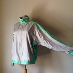 Puede incluir: Chaqueta deportiva gris y verde menta con cierre de cremallera completo. La chaqueta tiene cuello alto y pu&ntilde;os y dobladillo el&aacute;sticos. Las mangas y los paneles laterales son verde menta, el cuerpo es gris.