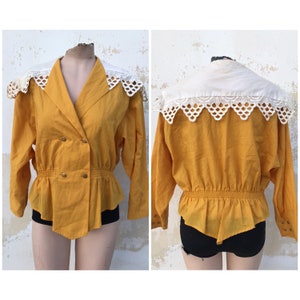 May include: Mustard yellow blouse with a white, scalloped collar. The long-sleeved top features a double-breasted design with gold buttons and a gathered waist. The back view shows the same collar and a gathered waist detail.