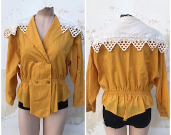 Dramática blusa de color amarillo mostaza de los años 80 con cintura elástica y cuellos de peregrino con cortes anchos. Acabado en punta en la parte delantera y trasera.