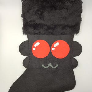 May include: Black plush Christmas stocking with a cute bug face. The bug has red eyes and a white smile.