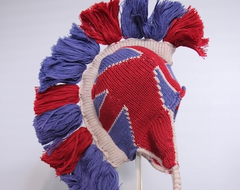 May include: A knitted hat with a mohawk style design. The hat is red, white, and blue with a Union Jack pattern. The hat has a long tassel.