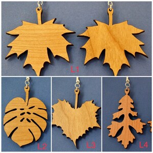 May include: Four different wooden leaf-shaped earrings with silver hooks. The leaves are in various shapes, including maple, monstera, heart, and pine tree.
