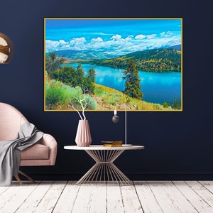 Puede incluir: Una fotograf&iacute;a de paisaje enmarcada de un lago rodeado de monta&ntilde;as y &aacute;rboles. El lago es de un azul vibrante y el cielo es de un azul claro con nubes blancas. Las monta&ntilde;as son de un verde oscuro y los &aacute;rboles son de un verde claro.