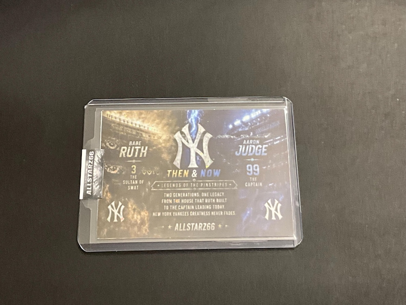 May include: A baseball trading card featuring Babe Ruth and Aaron Judge. The card is encased in a protective sleeve and includes the text "Then & Now" and "Legends of the Pinstripes". The card also displays the New York Yankees logo.